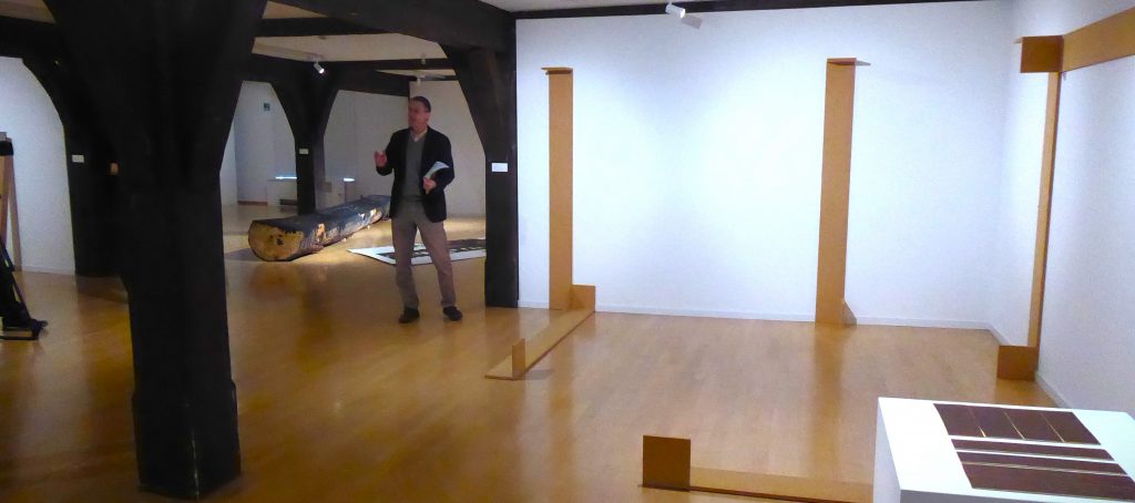 Kurator Rainer Lawicki bei der "Holz"-Ausstellung mit Werken von Chrisdtian Wulffen und Felix Droesens (flachgelegter) "Hölderlinsäule im Hintergrund. Foto: Martin Bernklau